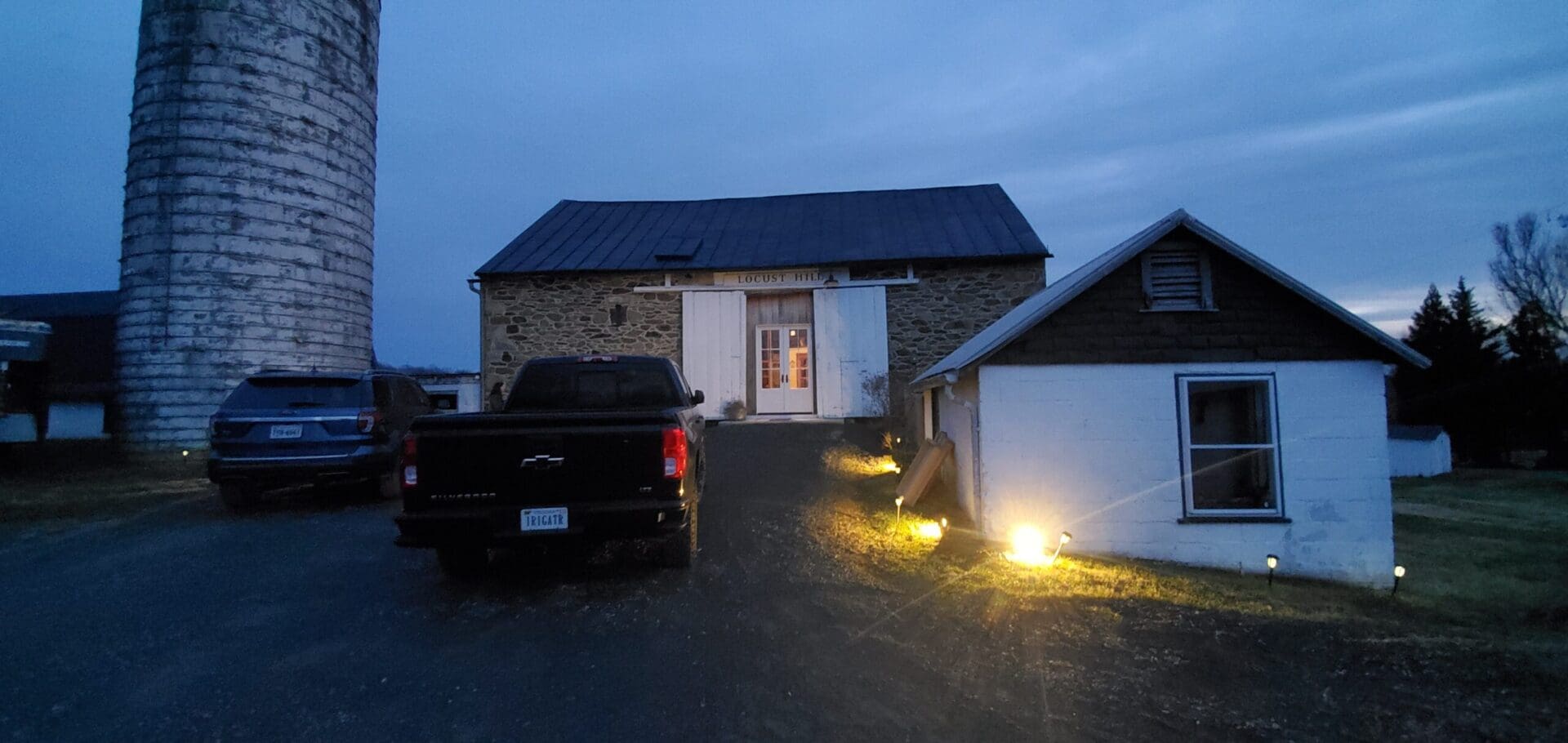 Evening farm scene with barn, silo, and trucks