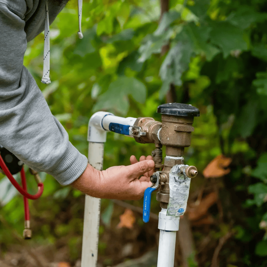 Hand turning outdoor water spigot on PVC pipe